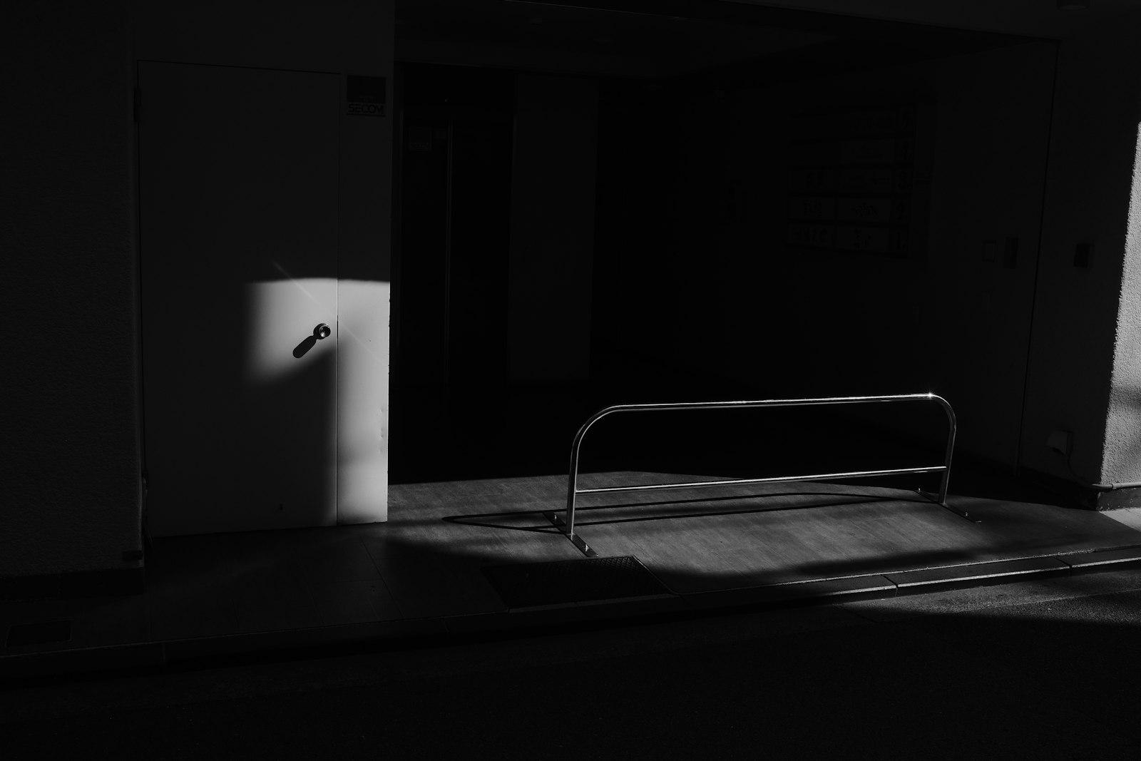 A dark doorway and polished rail cut by a strip of afternoon light.